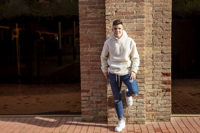 Portrait of young man leaning against brick wall