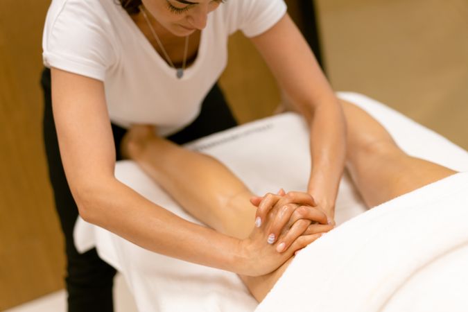 Massage therapist applying pressure to a client’s legs