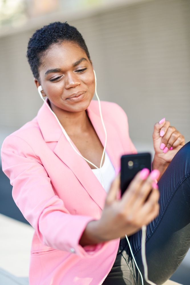 Happy female wearing suit with pink jacket talking on video call
