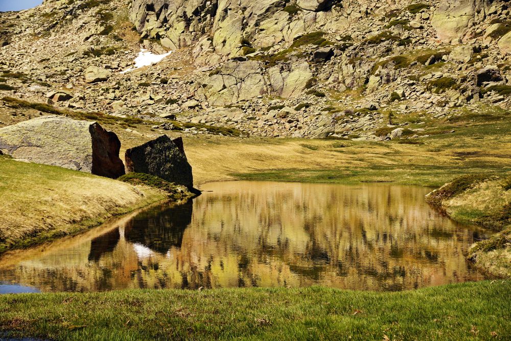 Clear lake at bottom of rocky mountain
