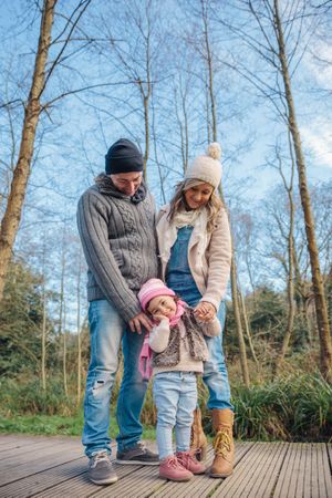 Mother and father standing with young daughter in forest