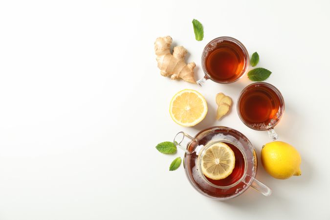 Flat lay. Cups with tea and teapot, lemon, mint and ginger, space for text