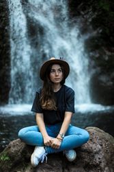 Smiling woman sitting near waterfall