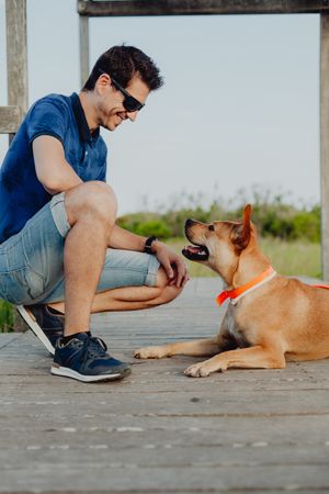 Happy adult man playing with dog at countryside