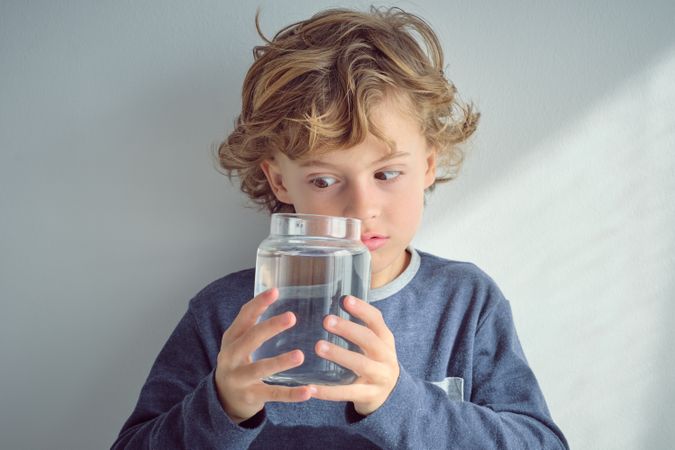 Curious boy looking inside jar with water