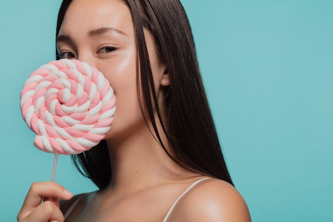 Portrait of young woman with a sugar candy lollipop