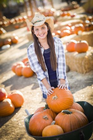 Preteen Girl Playing with a Wheelbarrow at the Pumpkin Patch.