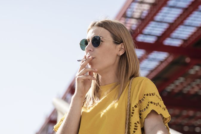 Stylish woman in sunglasses smoking