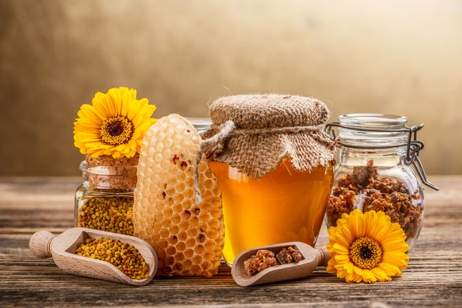 Pot of honey, honey comb and pollen on wooden table 