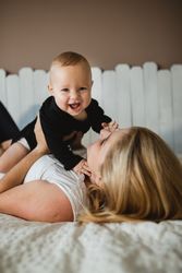 Mother playing with baby on bed