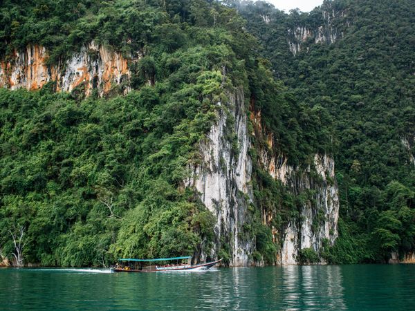 Tourism boat on river near green trees and mountain