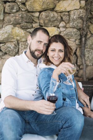 Couple relaxing sitting on a terrace while bonding and enjoying a cup of wine