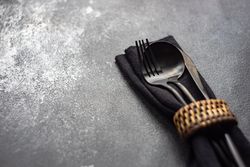 Dark silverware in matching napkin on counter with copy space