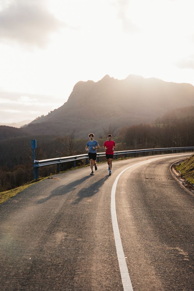 Sportsmen running on asphalt road in mountains