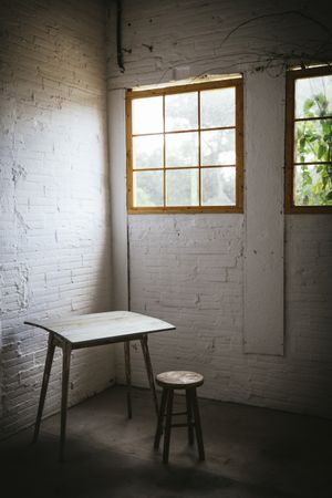Concept of table near stool in grey murk room with brick walls