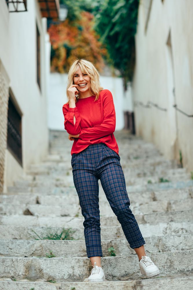 Happy blonde woman with red shirt standing on steps outdoors