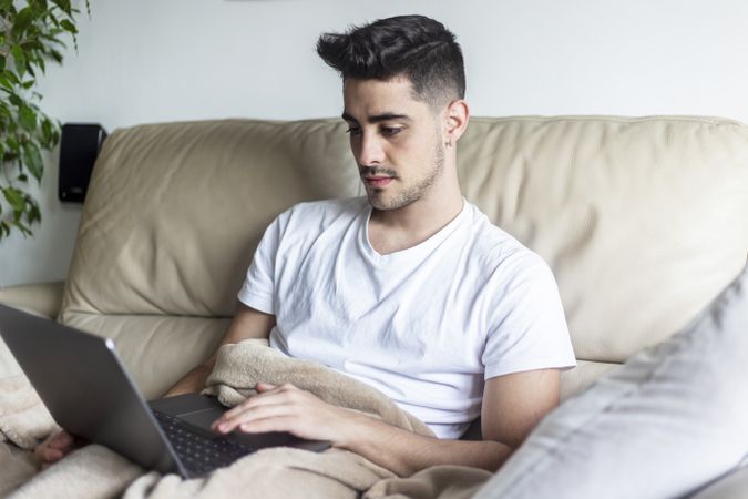 Man relaxing on sofa using laptop