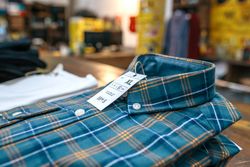 Detail of label with price and size over a blue plaid shirt on industrial style store