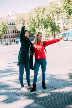Cheerful women greeting friend on street