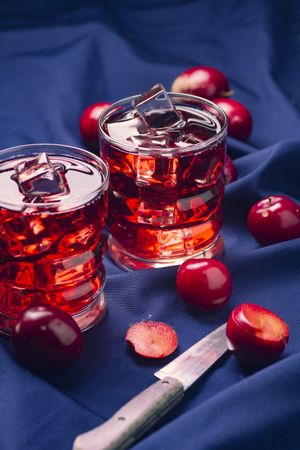 Red beverage near fresh fruits on cloth