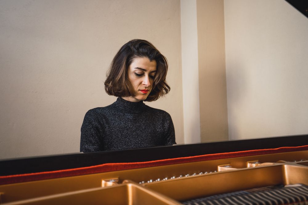 Young woman playing notes behind a piano