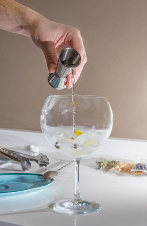 Barman pouring drink to prepare gin tonic cocktail