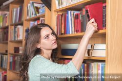 Woman picking a book from a library 5qLmq0