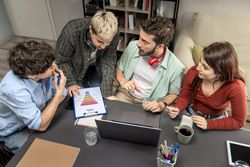 Overhead view of diverse creative team analyzing marketing funnel on laptop