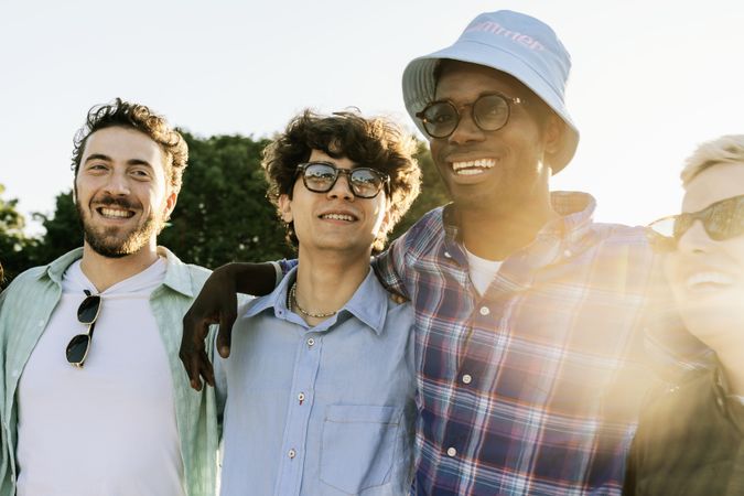 Happy diverse group of young friends smiling at sunset during summer outdoor gathering