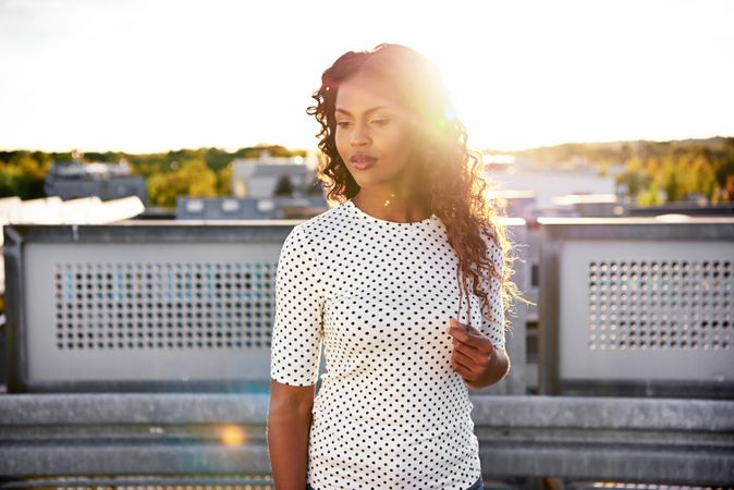 Radiant Black woman in spotted shirt on sunny roof