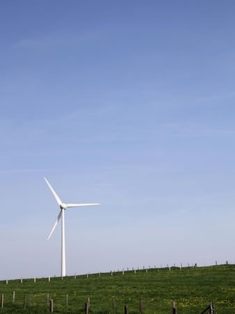 Wind turbine on green grass field under blue sky
