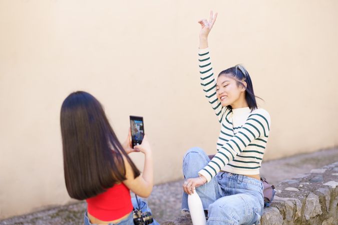 Woman smiling with hand above her head while her friend takes her picture