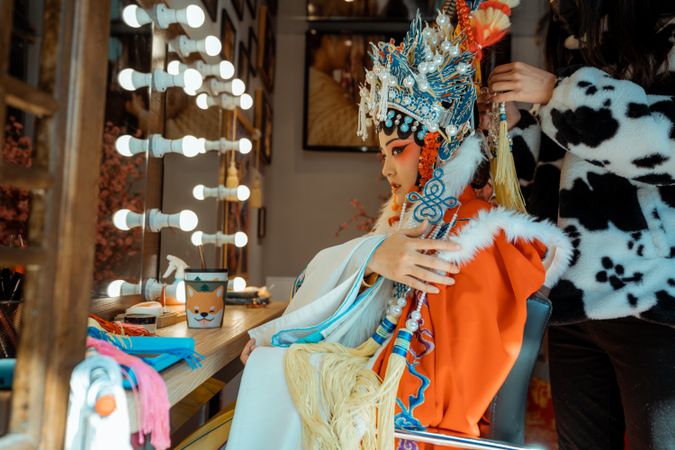 Side view of Chinese actress in her cultural outfit getting ready for stage performance