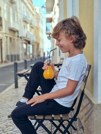 Cheerful boy drinking juice in city