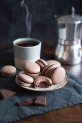 Freshly baked chocolate macarons with hot coffee