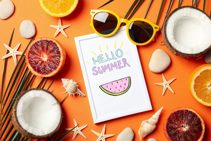 Frame with Hello summer and vacation accessories on orange background, top view