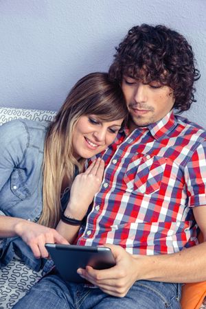 Happy affectionate couple in love looking at electronic tablet in bed