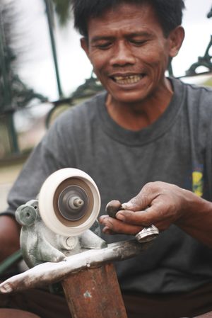 Man shaping stones on a wheel for jewelry