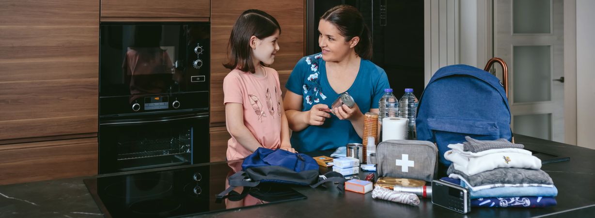 Mother explaining to her daughter how to prepare emergency backp