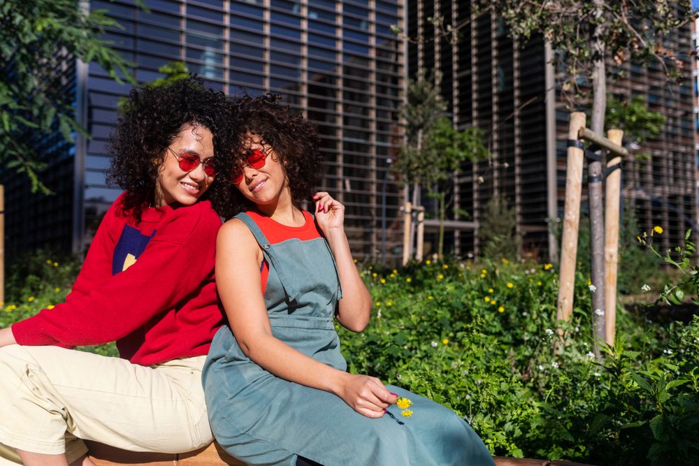 Female couple sitting back to back on bench outside