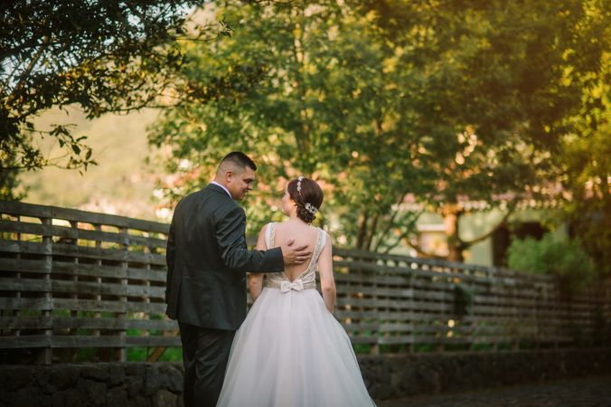 Smiling groom and bride hugging and kissing in park