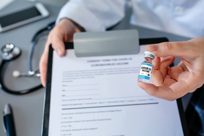 Female doctor's hand showing coronavirus vaccine vial