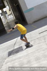 Back view of a male skateboarder in yellow riding on a sunny day 4jVOx8