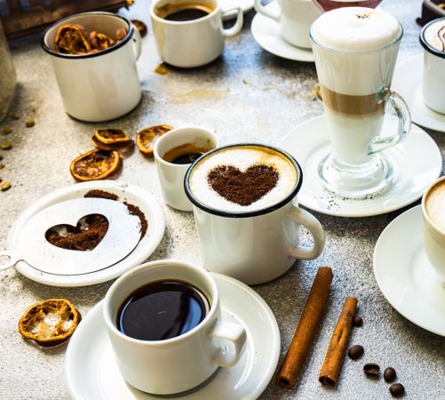 Coffee drinks on table with cinnamon sticks and dried orange