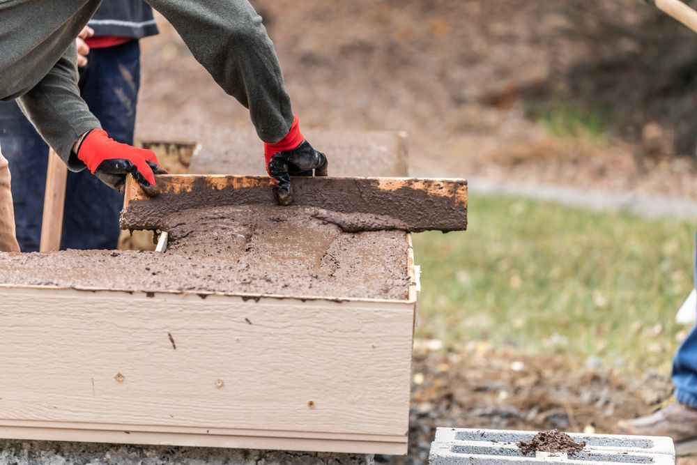 Construction Worker Leveling Wet Cement Into Wood Framing
