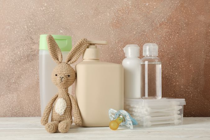 Baby hygiene accessories on wooden table against brown background