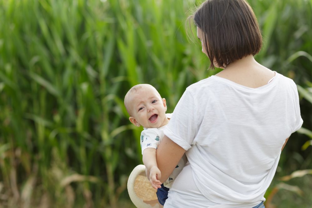 Adorable mother and child on hand enjoying and laughing in field