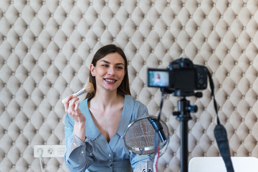 Happy woman applying powder and recording video on camera
