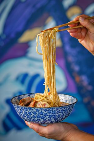 Crop person using chopsticks while eating Japanese noodle soup