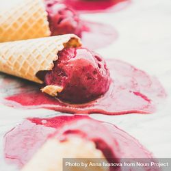Close up of cones of dark berry ice cream melting on marble slab, square crop 48Mzkb